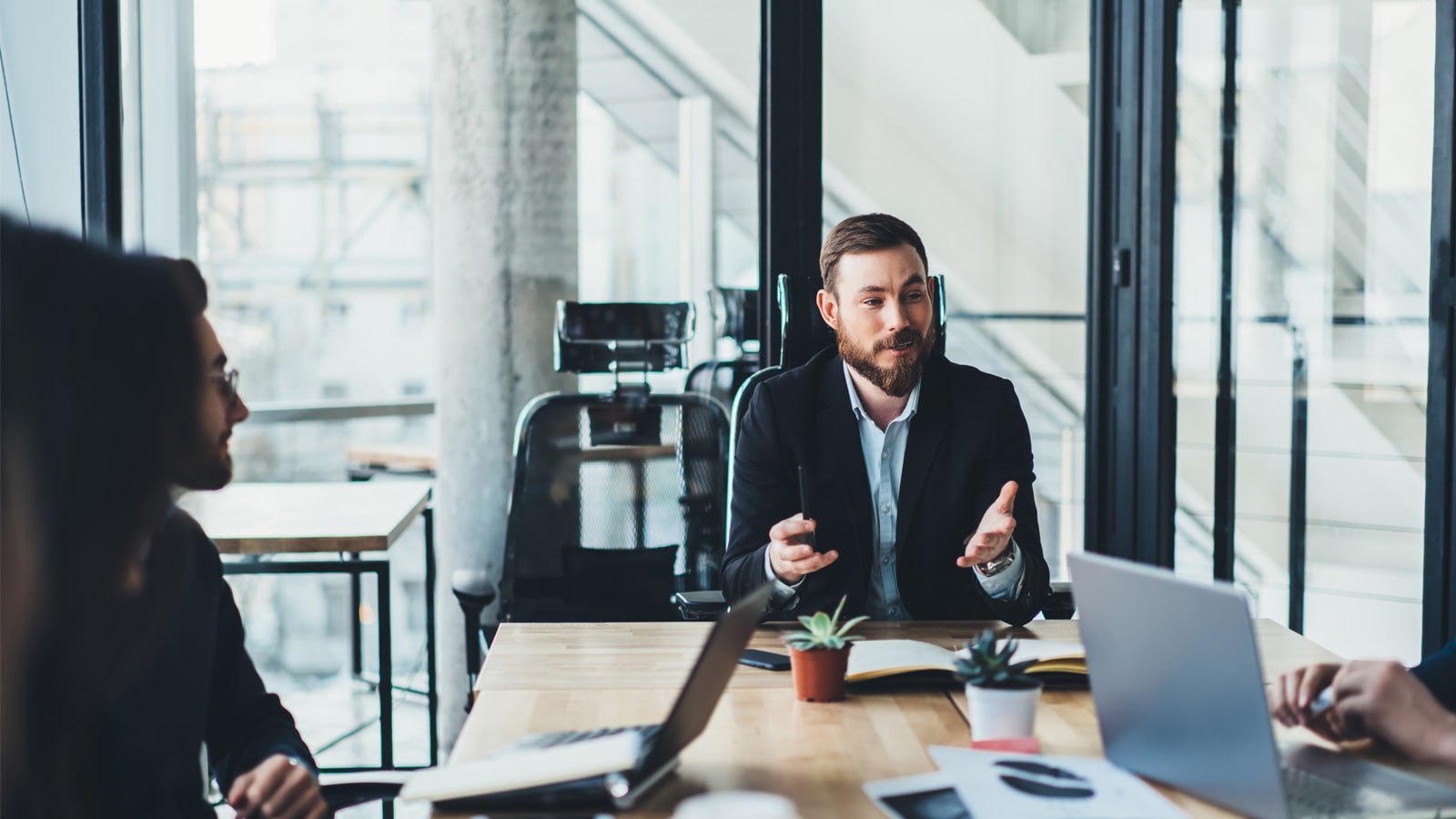 Man sitting at a desk in an office talking to colleagues