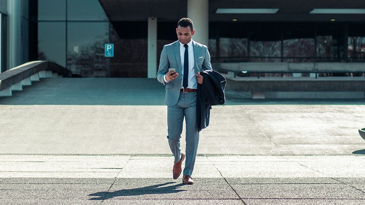 A man in a suit walking down steps reading his phone